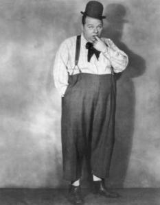 circa 1920: A full-length studio portrait of the silent screen comedic actor Fatty Arbuckle (1887-1933) wearing a black hat and sticking his finger in his mouth. (Photo by Mitchell/Hulton Archive/Getty Images)